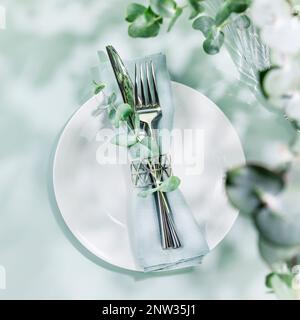 Sustainable spring holiday table settings on blue background with eucalyptus leaves and shadows. Romantic summer holiday still life with setting suita Stock Photo
