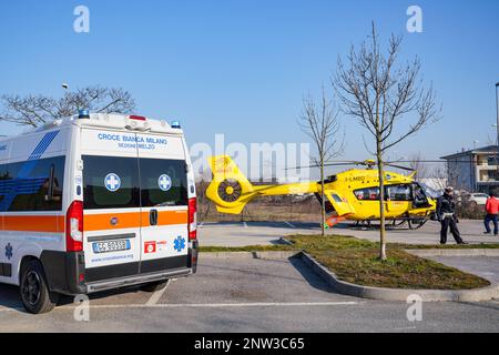 Ambulance and Medical helicopter landed in the background in a public car parking, in Cernusco sul Naviglio, Italy, on February 10, 2023 Stock Photo