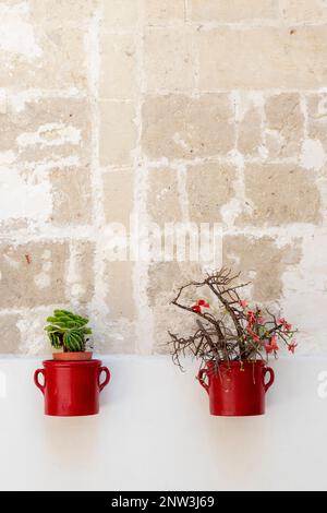 Two small flower pots hanging on a wall in the town of Grottaglie, Puglia, Italy Stock Photo