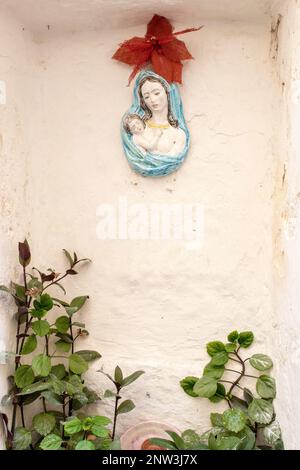 A ceramic decoration depicting the Virgin Mary and baby Jesus hanging on a wall in Grottaglie, Puglia, Italy Stock Photo