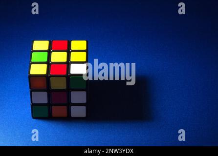 Partially lit puzzle cube on a blue table top Stock Photo