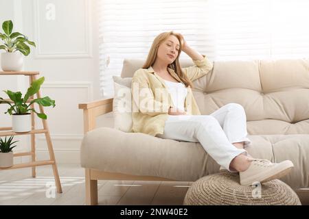 Beautiful young woman relaxing on sofa at home Stock Photo