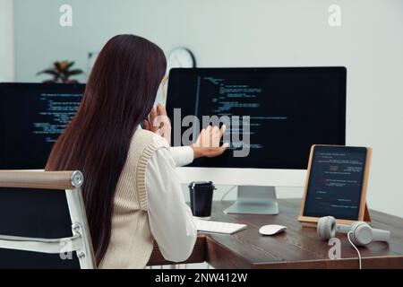 Programmer talking on phone while working at desk in office Stock Photo