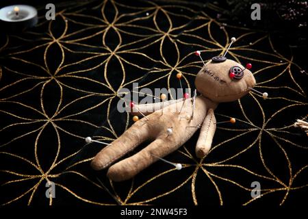 Voodoo doll pierced with pins on table. Curse ceremony Stock Photo