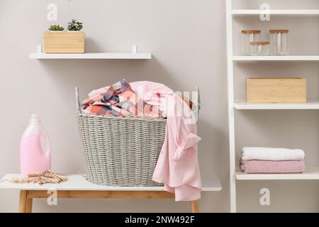 Wicker basket with dirty laundry on table indoors Stock Photo
