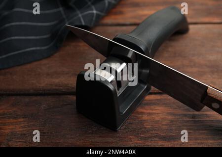 Modern handheld sharpener and knife on wooden table Stock Photo