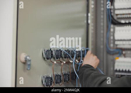 electrician working on electric panel, closeup of hands with wires Stock Photo