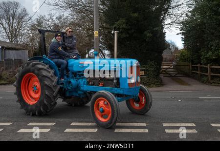 A couple drive along in a vintage Fordson Super Major tractor in Wisborough Green, West Sussex, UK. Stock Photo