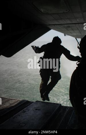 A U.S. Marine with Alpha Company, 2nd Reconnaissance Battalion, jumps out the back of a CH-53E Super Stallion during helocast water insert training, Feb. 14, 2023. Helocasting is an airborne technique that allows Marines to stealthily insert from a helicopter into any body of water in order to utilize Combat Rubber Raiding Craft to conduct amphibious beach reconnaissance and raids. Stock Photo