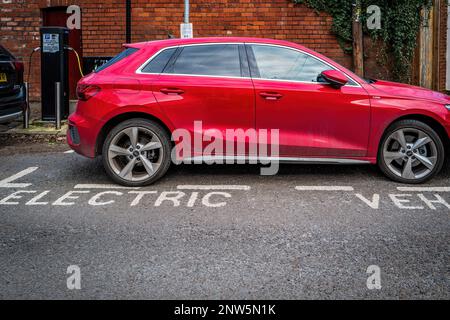 Electric Vehicle (EV) being charged up at a charging point in a suburban street in Cardiff, Wales, UK.  Electrification of transport. Concept. Stock Photo