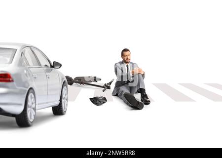 Businessman with an electric scooter sitting on a pedestrian crossing and holding his painful knee isolated on white backgroundd Stock Photo