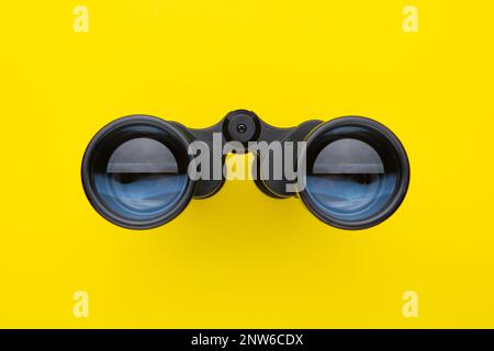 Binoculars isolated on yellow background. Stock Photo