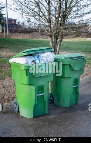 Vertical shot of two full trash containers by the curb. Stock Photo