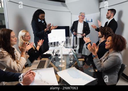 Teamwork with diverse ethnicity is sitting at office clapping hands celebrating a new idea project exposed by the team leader. Stock Photo