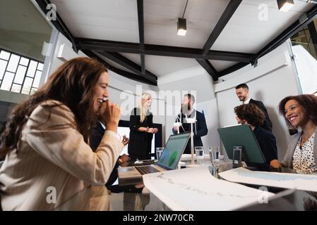 Multiracial group of businesspeople working on a business plan siting at desk in office. Teamwork enjoy work together. Stock Photo