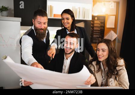 Mixed race group of young business people looking a blueprint in office. Stock Photo