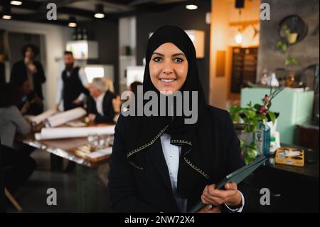 Portrait of arabic businesswoman with veil in workplace. Colleagues have a meeting. Stock Photo