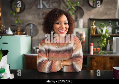 Portrait of smiling latin woman looking at camera smiling. Female in her kitchen. Stock Photo