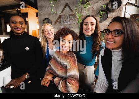 Group of five multiracial females in casual clothes smiling looking at camera. Stock Photo