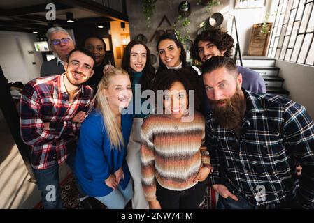 Wide angle portrait with group of mixed race and age looking at camera smiling. Stock Photo