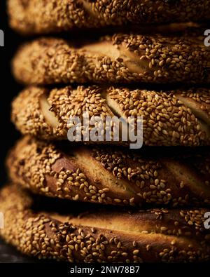 Close up ofTurkish simit bread pretzels stack. Homemade Sesame bagel on dark background. Low key, dark photo Stock Photo