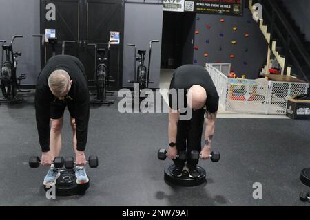 U.S. Army Reserve Chief Warrant Officer 2 Donald Smith, left, and Sgt. Samuel Hellerude, assigned to the Headquarters and Headquarters Detachment, 88th Readiness Division, Fort McCoy, Wis., stretch with dumb bells at a Cross Fit gym in Sparta, Wis., Jan. 8, 2023.  The training event was a partnership with the Sparta facility and part of the Division's Holistic Health and Fitness implementation. Stock Photo