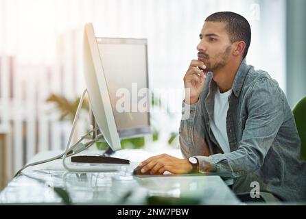 Problem solving is his specialty. Shot of a young designer working at his computer in an office. Stock Photo
