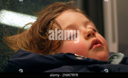 Candid child sleeping in train. Closeup small boy asleep on mother lap while traveling. Kid napping Stock Photo