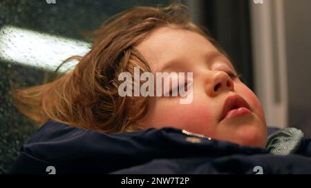 Candid child sleeping in train. Closeup small boy asleep on mother lap while traveling. Kid napping Stock Photo