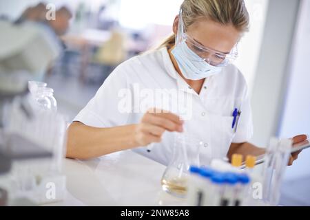 Testing a theory. A young scientist conducting an experiment in her lab. Stock Photo