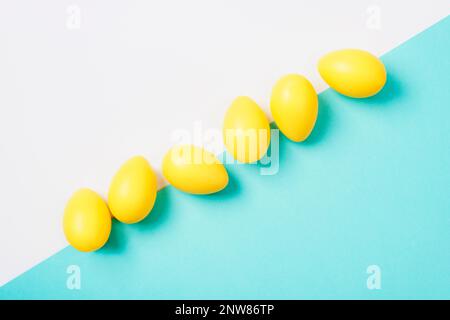 Yellow Easter eggs on white and blue background. Top view, flat lay, copy space. Stock Photo