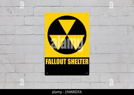 Yellow warning sign screwed to a brick wall to warn about a threat. In the middle of the panel, there is a nuclear symbol and the message is saying 'F Stock Photo