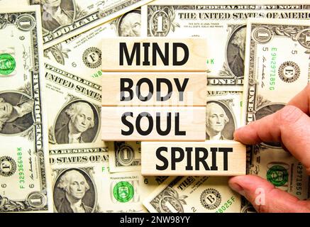 Mind body soul spirit symbol. Concept words Mind Body Soul Spirit on wooden blocks. Beautiful background from dollar bills. Businessman hand. Lifestyl Stock Photo