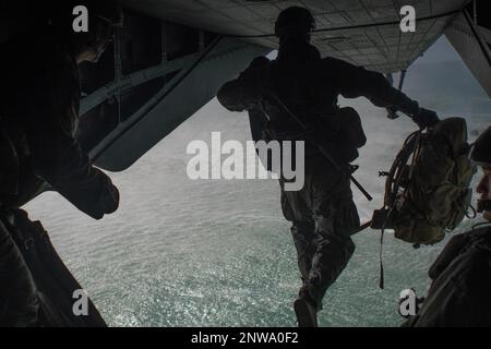 A U.S. Marine with Alpha Company, 2nd Reconnaissance Battalion, jumps out the back of a CH-53E Super Stallion during helocast water insert training, Feb. 14, 2023. Helocasting is an airborne technique that allows Marines to stealthily insert from a helicopter into any body of water, subsequently utilizing Combat Rubber Raiding Craft to conduct amphibious beach reconnaissance and raids. Assisting in this training shows the capability of the MEU to conduct an insert of ground forces by sea. Stock Photo