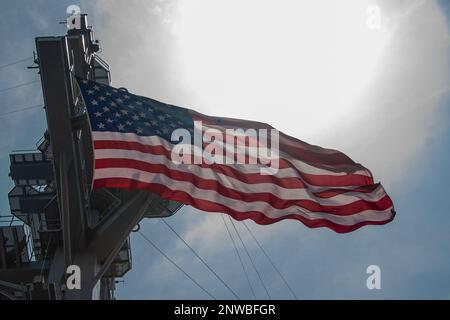 230215-N-FJ237-1148 SOUTH CHINA SEA (Feb. 15, 2023) The ensign flies aboard the aircraft carrier USS Nimitz (CVN 68). Nimitz Carrier Strike Group (NIMCSG) and Makin Island Amphibious Ready Group (MKI ARG), with embarked 13th Marine Expeditionary Unit (13th MEU), are conducting combined expeditionary strike force (ESF) operations, demonstrating unique high-end war fighting capability, maritime superiority, power projection and readiness. Operations include integrated training designed to advance interoperability between the two groups while simultaneously demonstrating the U.S. commitment to ou Stock Photo