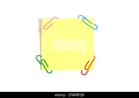 Yellow paper sticker for written notes and paper clips on a white background Stock Photo
