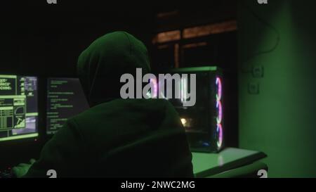 Hacker in Hoodie Hacking Away with Back Turned Stock Photo