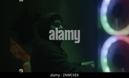 Glasses-wearing programmer or hacker working on desktop computer with green lights in side view Stock Photo
