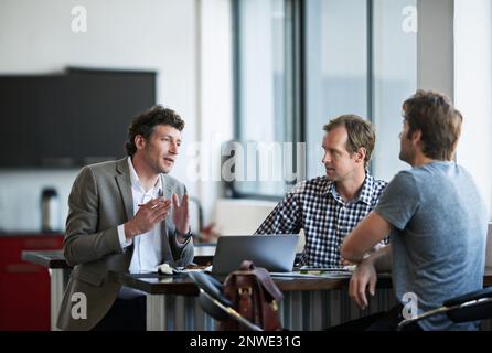 So heres my idea.... Cropped shot of three businessman discussing work in the office. Stock Photo