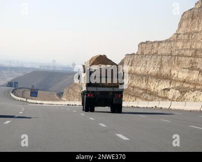 Giza, Egypt, January 26 2023: A big truck loaded with large blocks of stone, limestone, rocks taken from quarries in mountains being transferred on a Stock Photo