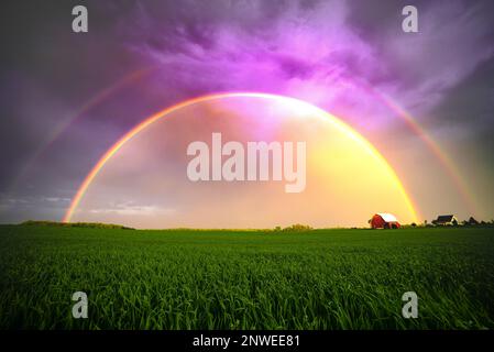 A stunning double rainbow seen in the farming prairies of the United States of America. Purple sky, vibrant landscape. Stock Photo