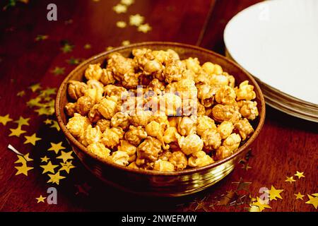 Bowl of Popcorn set on a rustic table decorated with gold stars Stock Photo