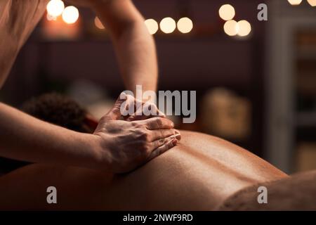 Massage therapist applying light touches when massaging back of client Stock Photo