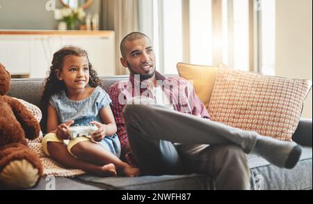 The only thing that cant be paused is bonding time. Shot of an adorable little girl and her father playing video games together on the sofa at home. Stock Photo