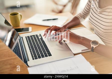 Staying on top of things. Cropped shot of an unrecognizable woman working on her laptop at home. Stock Photo