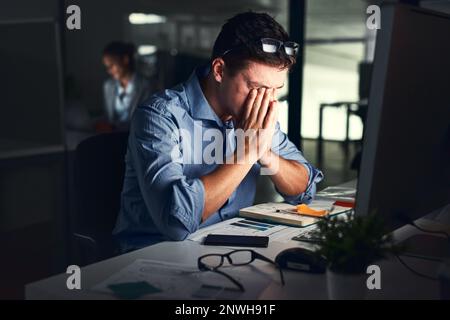 Feeling the strain of working late. Shot of a young businessman working late at night in a modern office. Stock Photo