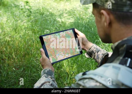 Soldier using tablet in forest, closeup view Stock Photo