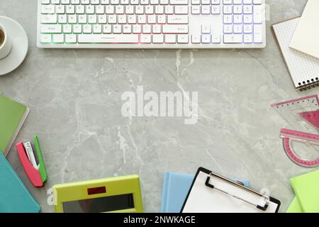 Frame of modern keyboard with RGB lighting and stationery on grey table, flat lay. Space for text Stock Photo