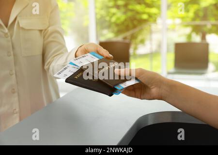 Agent giving passports and tickets to woman at check-in desk in airport, closeup Stock Photo