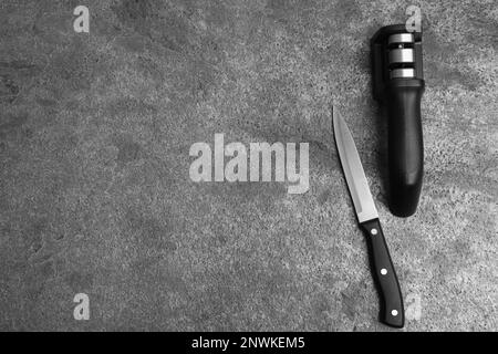 Modern handheld sharpener and knife on grey table, flat lay. Space for text Stock Photo